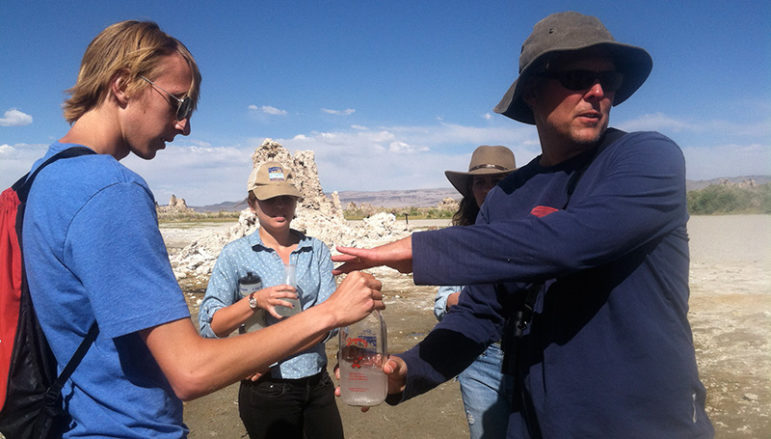 Visitors at the shore of Mono Lake demonstrating how tufa are created underwater from minerals combining.