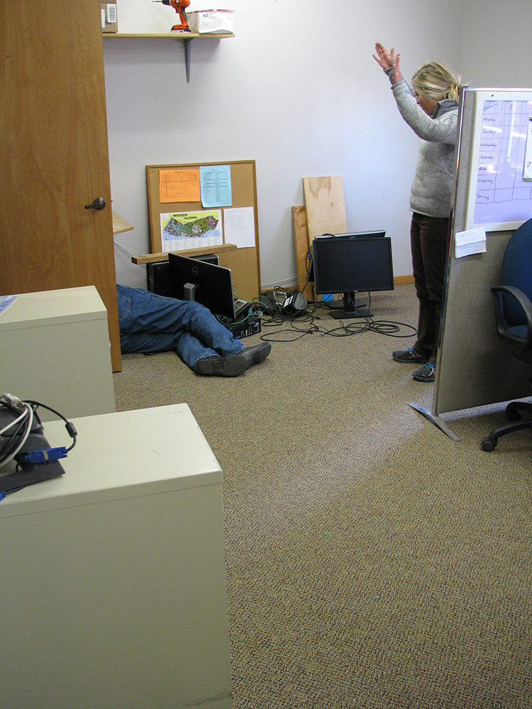 While Mister Fixit Vern Gersh reassembles a desk, Office Director Jessica Horn celebrates how nicely the carpet complements the color of the walls that she just finished painting. Photo by Elin LJung.