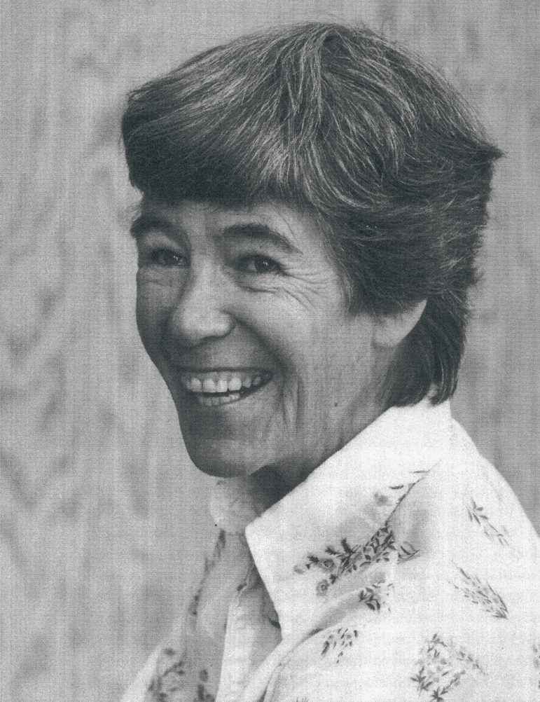 A black and white close up of a woman with short dark hair smiling and laughing at the camera.