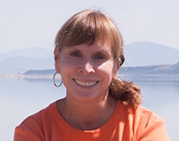 Woman smiling looking straight into the camera with Mono Lake in the background.