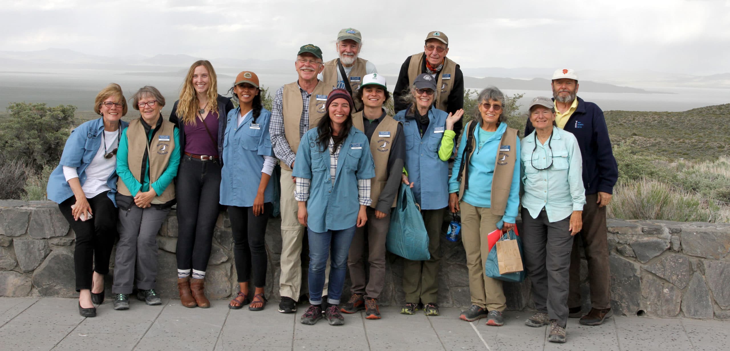 Thirteen people are standing together for a group photo smiling and looking very cheerful as they've just graduated to become official Mono Lake Volunteers.