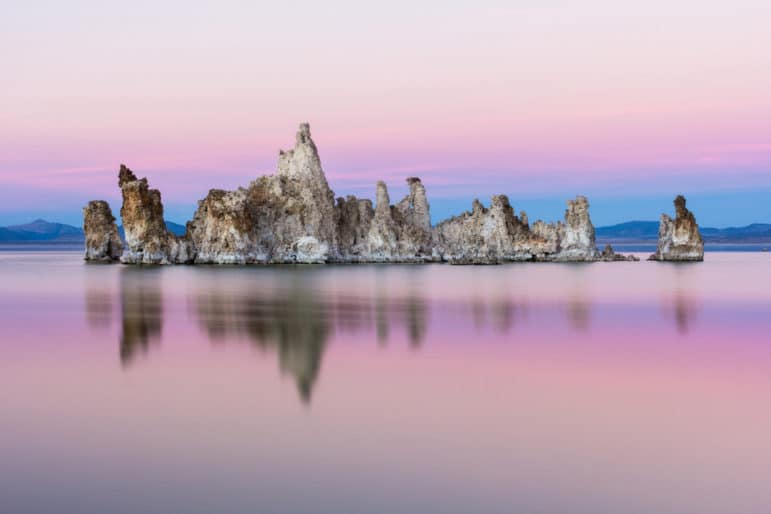 An island of tufa towers emerges from Mono Lake in a pink and blue soft hue sunset.