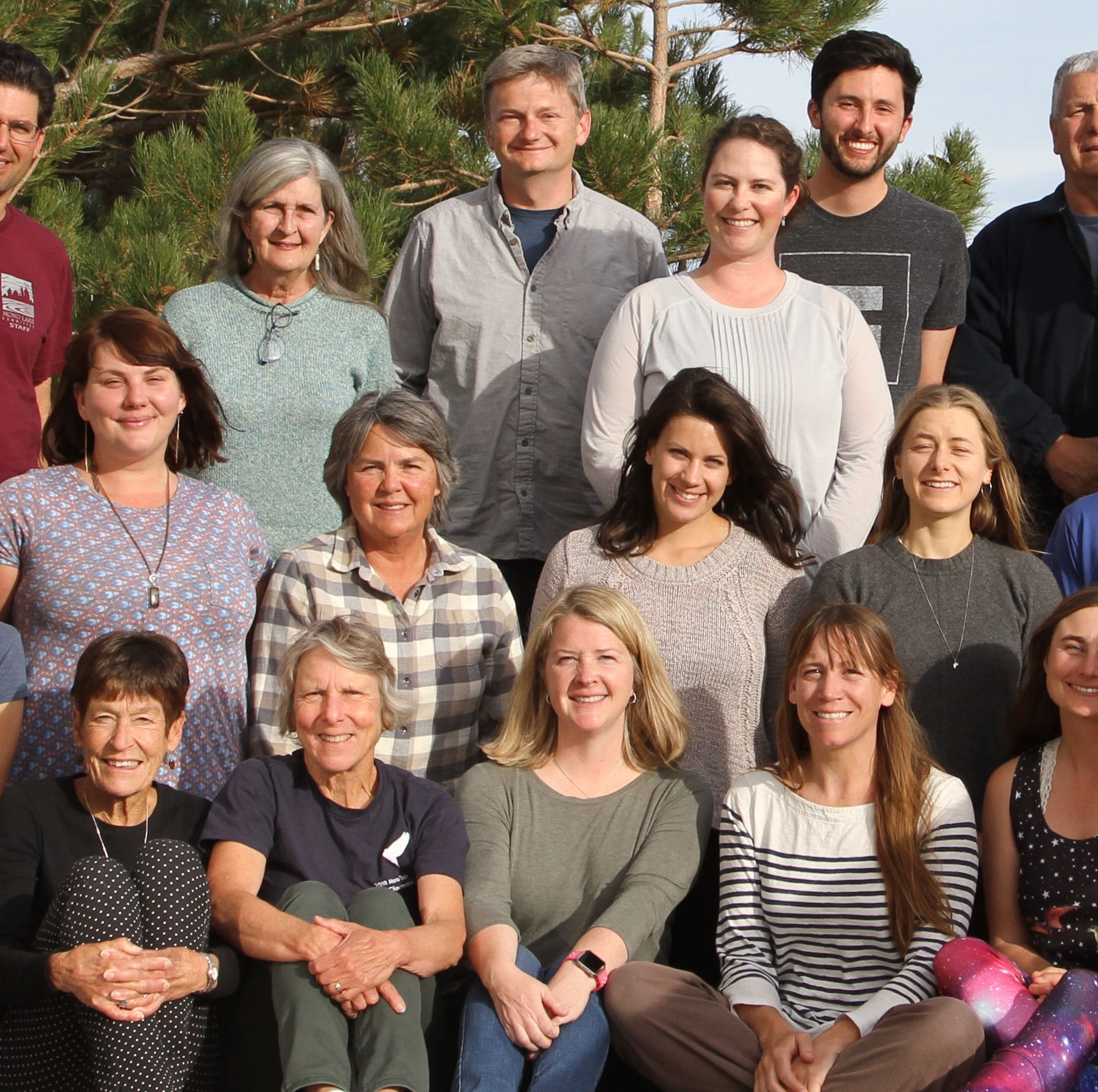 The Mono Lake Committee staff poses for a group photo ouside and are smiling and looking happy and proud.