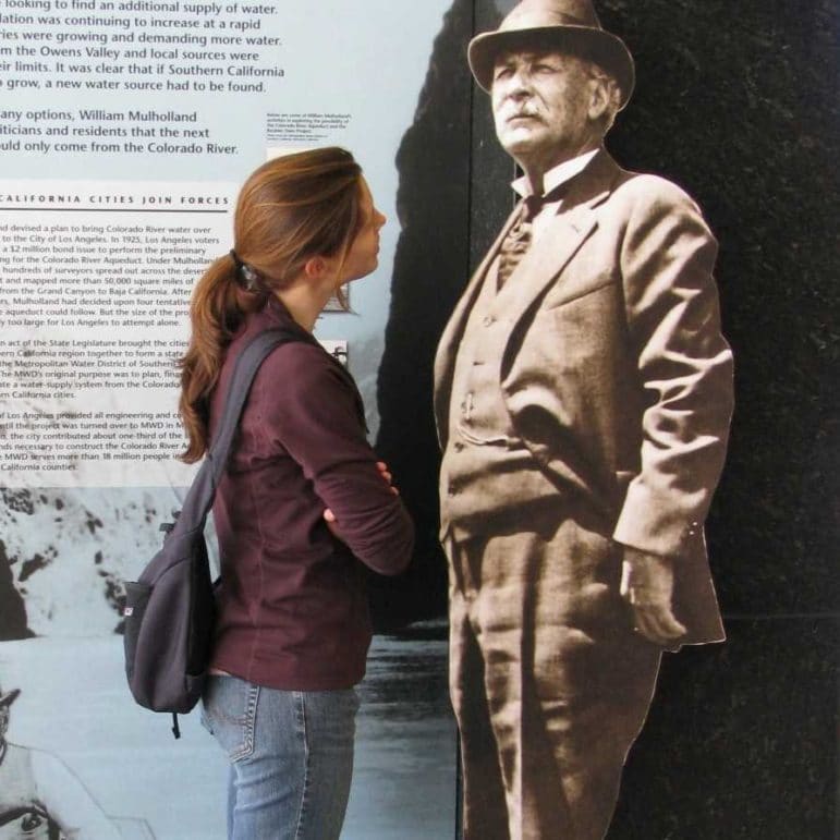 Arya Harp looking at a life-sized picture of William Mulholland.