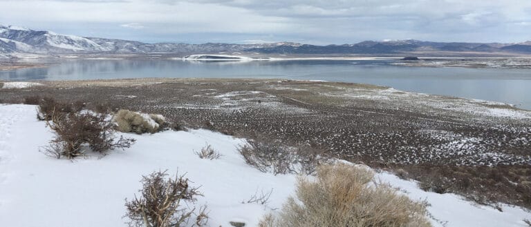 The view from Panum crater shows the snow speckled shore and the snow covered islands in the blue-gray Mono Lake water.