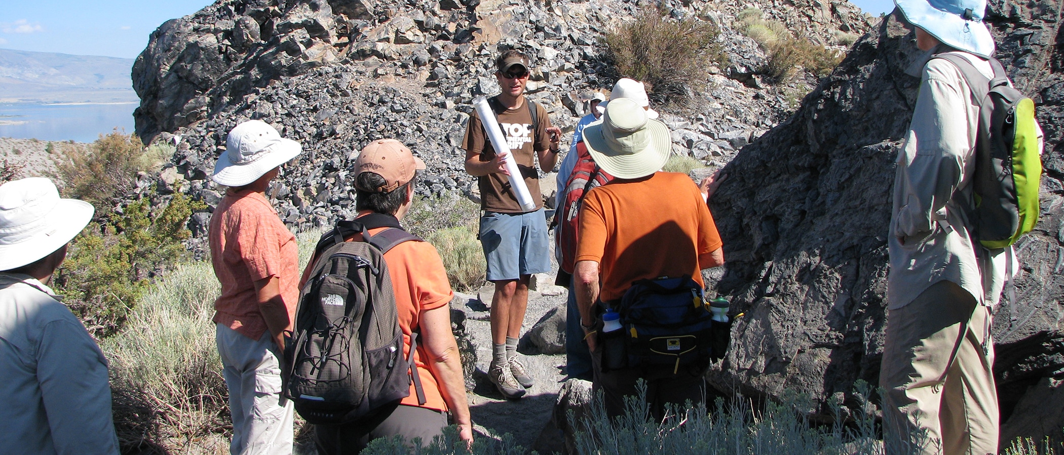 A man talks to a group in a rocky pathway.