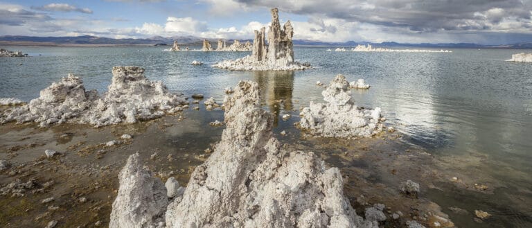 Tufa rise out of Mono Lake's lowered elevation with a cloudy sky overhead.