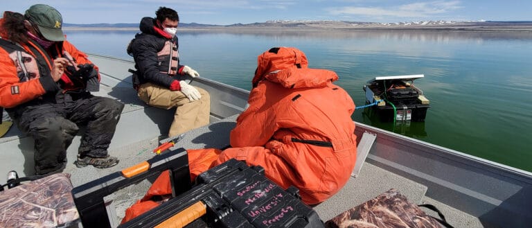 Scientists with the USGS working in a boat with research equipment beside it in Mono Lake.