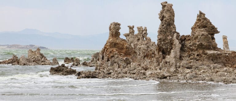 Tufa against hazy skies, small waves roll into the shore.