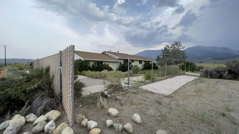 The Outdoor Educuation Center house with a partially dismantled fence,the sky is overcast.