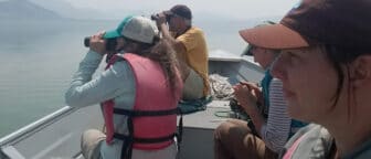 People looking through binoculars in a boat surrounded by smoke.