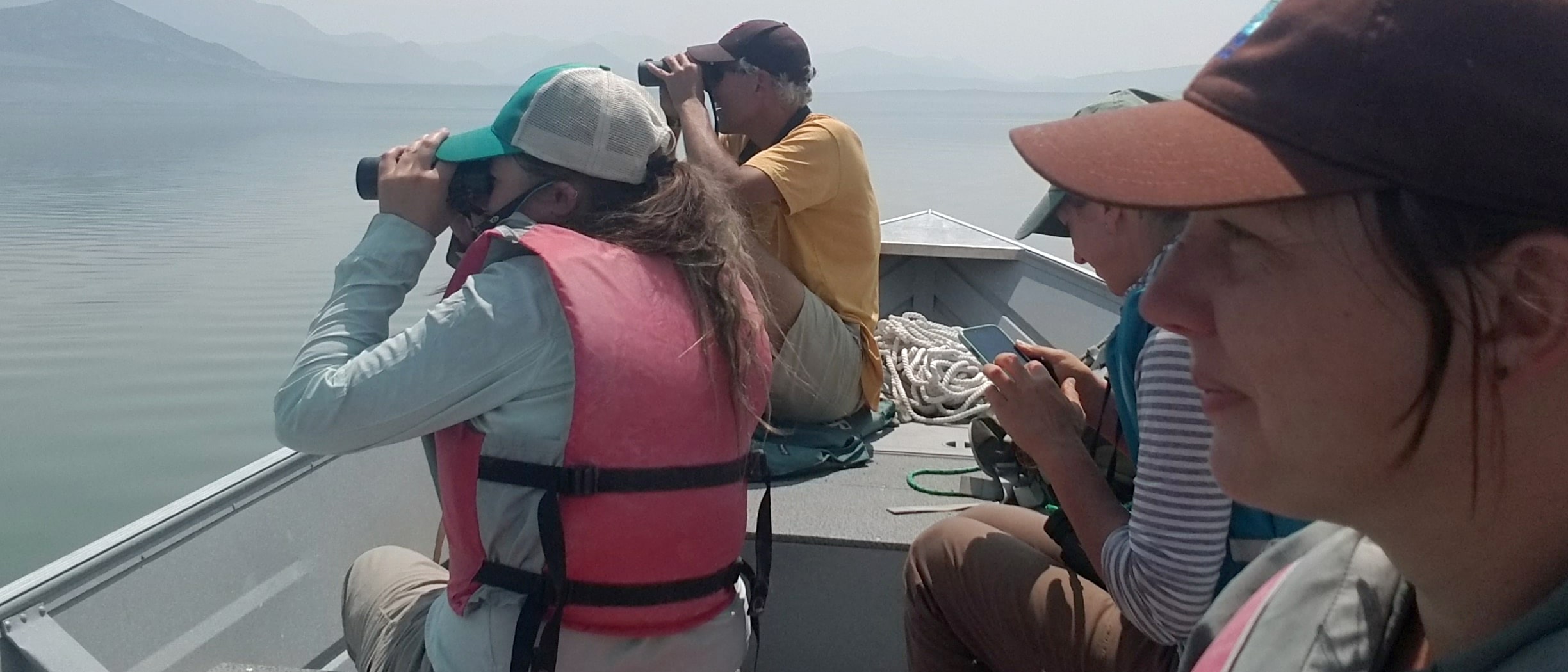 People looking through binoculars in a boat surrounded by smoke.