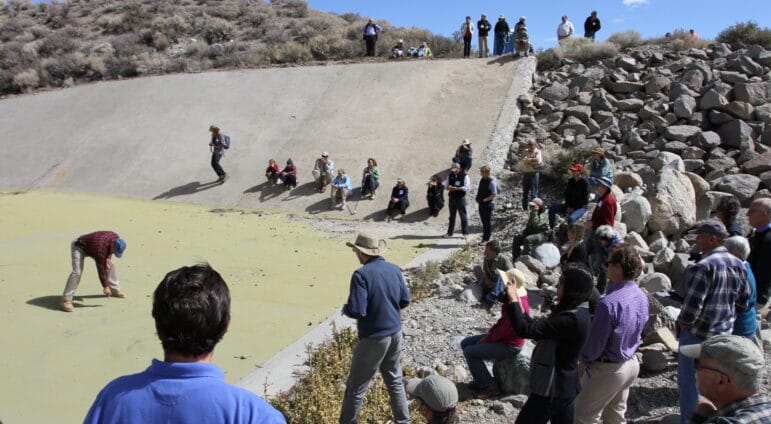 Former DWP Director of Water Operations Marty Adams sketches the conceptual Grant Reservoir outlet plan on the Grant Reservoir spillway with people looking on.