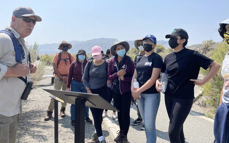 Santiago Escruceria talking with students in front of an interpretive sign along a pathway at South Tufa.