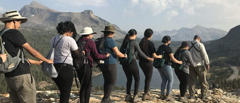 A row of people in front of mountains.