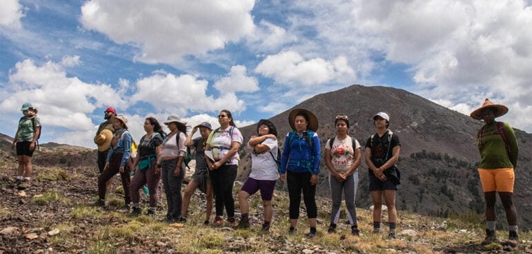 Students taking in the view with mountains and puffy white clouds behind them.