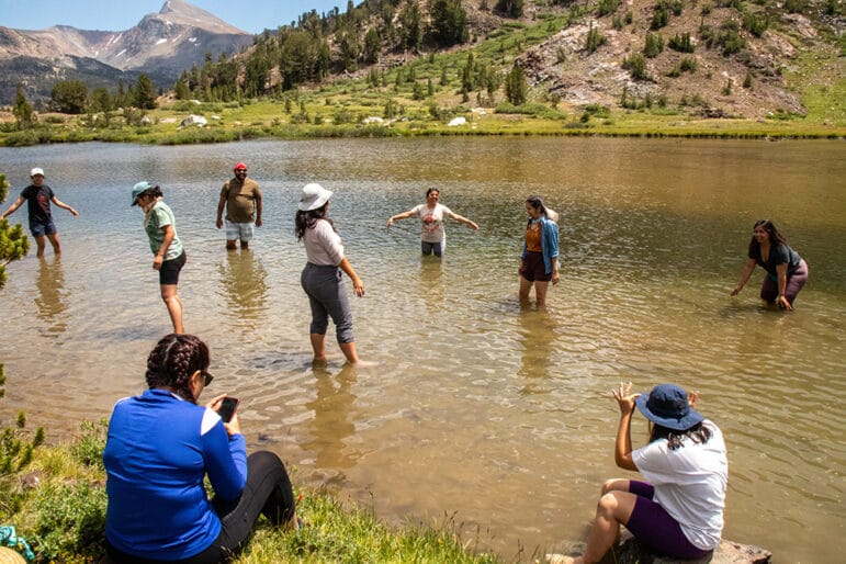 People wading in a high mountain lake.