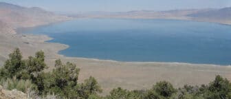 Walker Lake ringed by mountains with pine trees in the foreground.