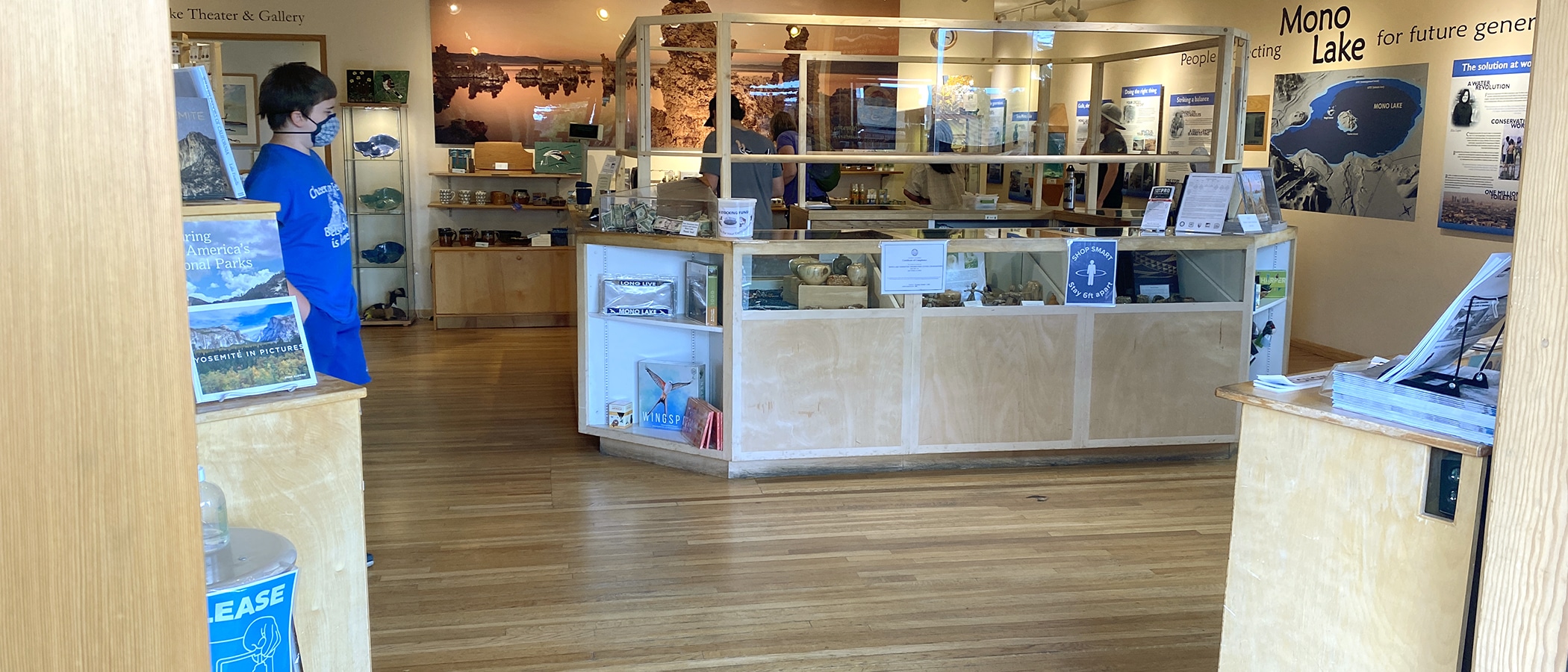 Counter of the Mono Lake Committee bookstore with masked people browsing the store.