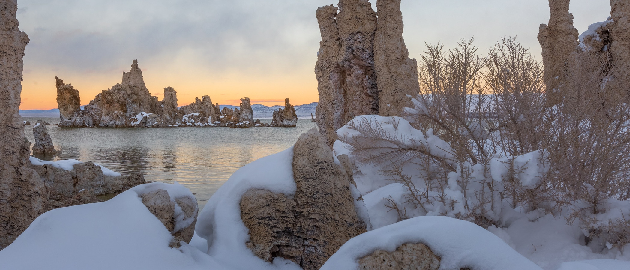 Snow covered tufa on the shore of Mono Lake with a pink edged horizon.